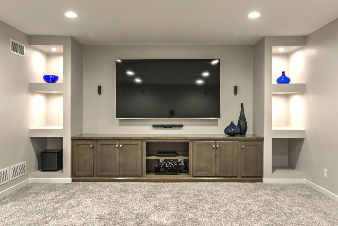 A finished basement with a TV on the wall for storage ideas