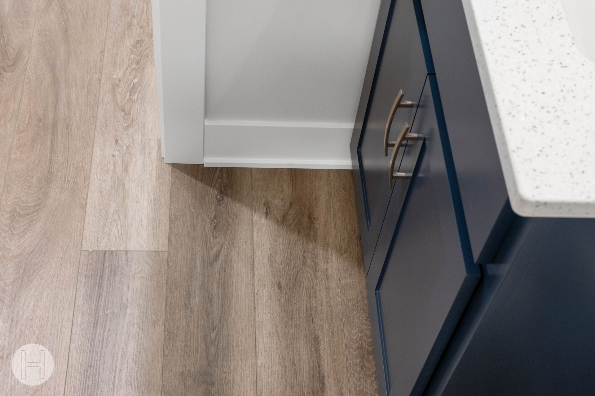 Best basement flooring with luxury vinyl plank installed beside modern navy blue cabinets and white quartz countertop